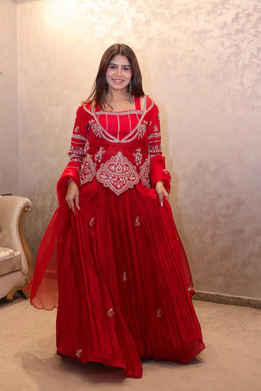 Woman wearing a red traditional outfit with intricate designs indoors.