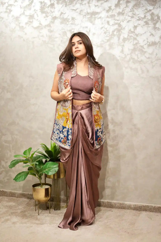 Woman in a traditional outfit with a floral jacket against a textured wall.